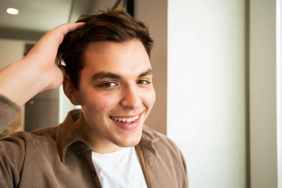 Smiling man running a hand through his full, natural-looking hair